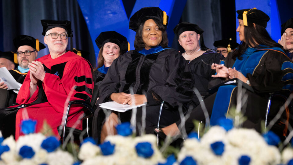 Audrey Gregory smiles from her seat on stage during Lynn's 2023 Commencement ceremony.