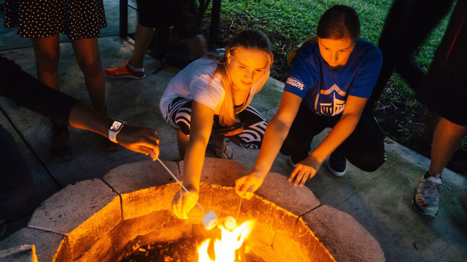 Students roasting marshmellows over the fire pit