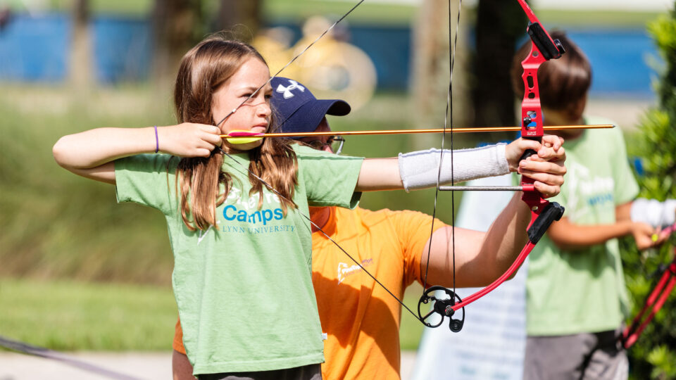 A counselor helps a camper with archery at Pine Tree Camps.