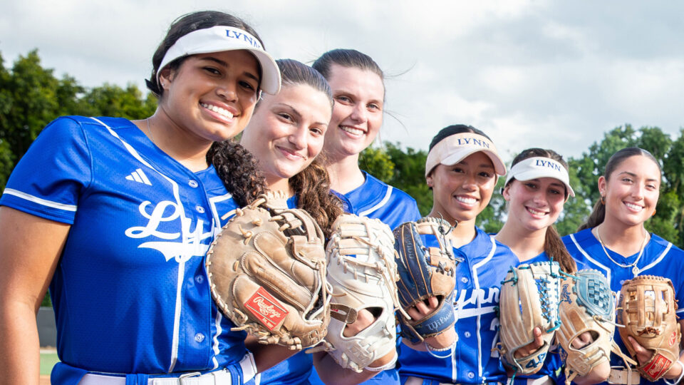 Lynn University's softball team takes a group picture with their uniforms and gloves.
