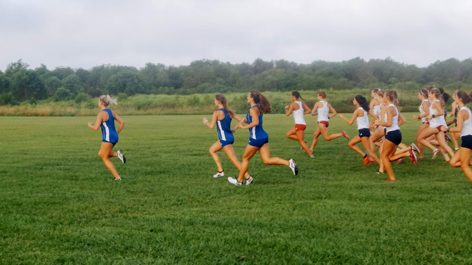 Female track students running on a field