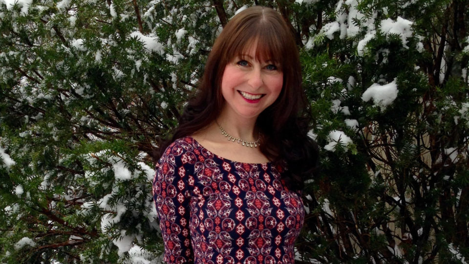 Jessica Sokol stands in front of a snowy tree.