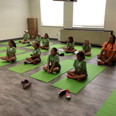 Campers doing yoga in a classrom on mats.