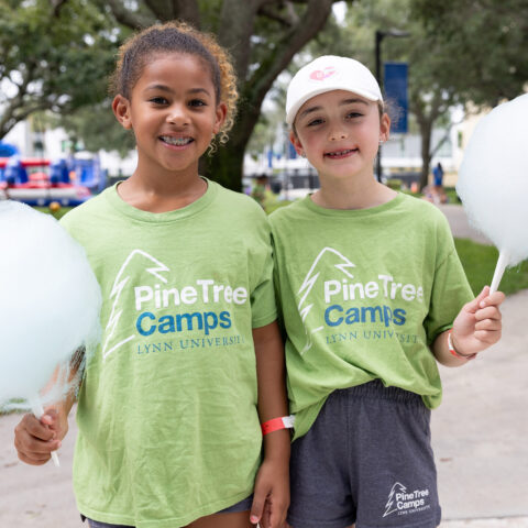 Two Pine Tree campers smile for the camera while holding cotton candy.